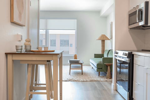 A kitchen with a bar stool and a table with a tray of bread on it.