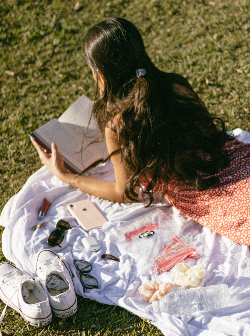 a woman sitting on the grass reading a book