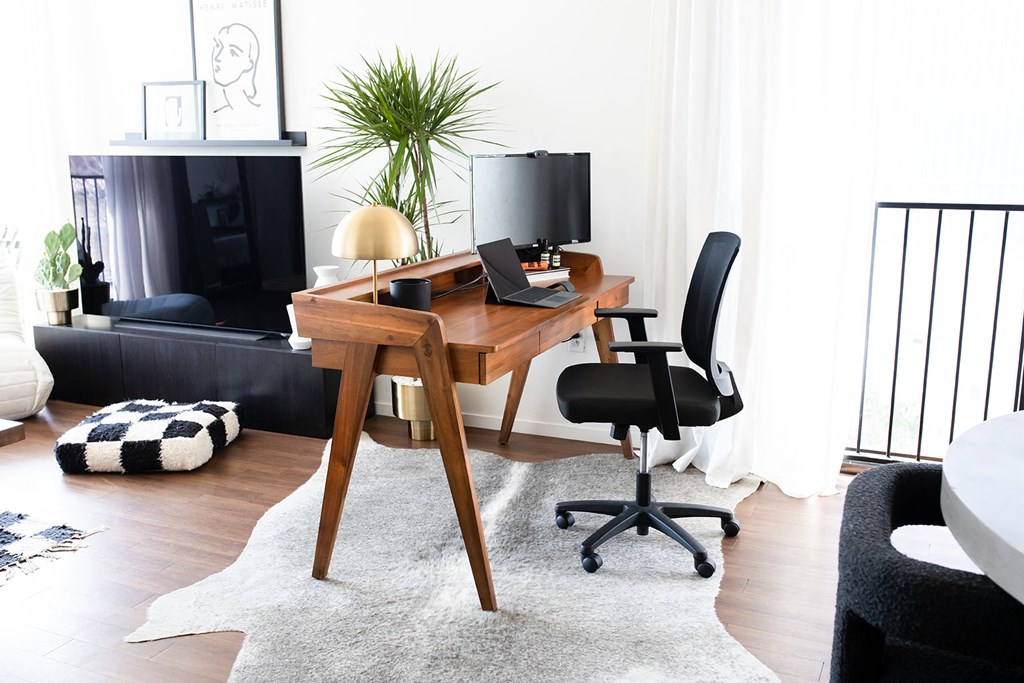 a living room with a desk with a computer and a chair