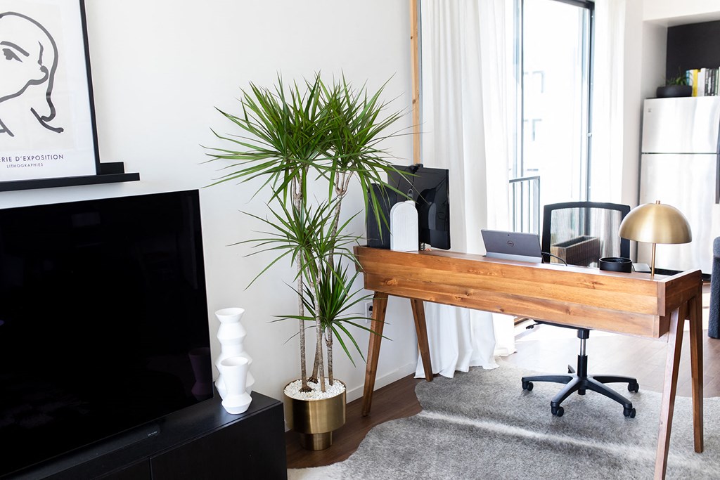 a living room with a desk and a television    and a large window