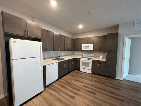 a kitchen with white appliances and wooden floors