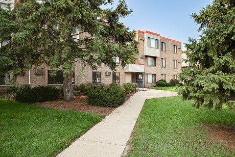 A building with a red stripe on the side is surrounded by greenery.