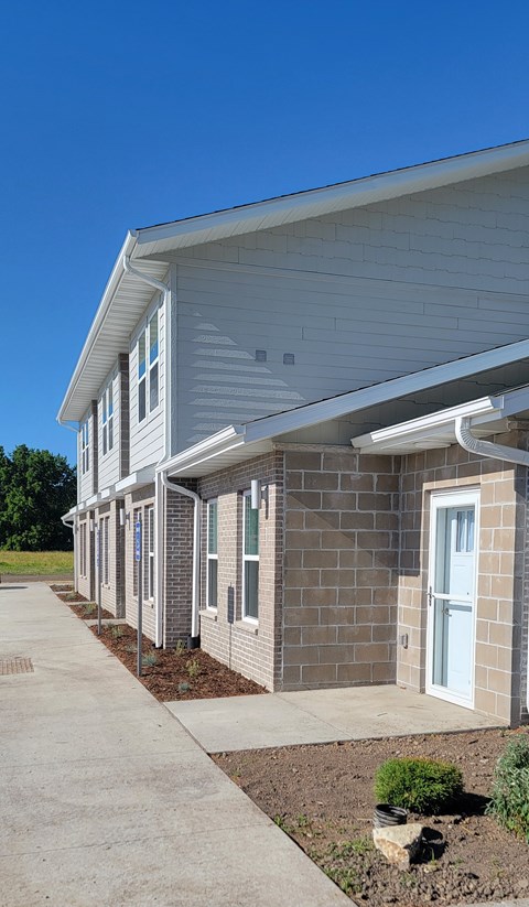 A building with a grey roof and white walls with a clear blue sky in the background.