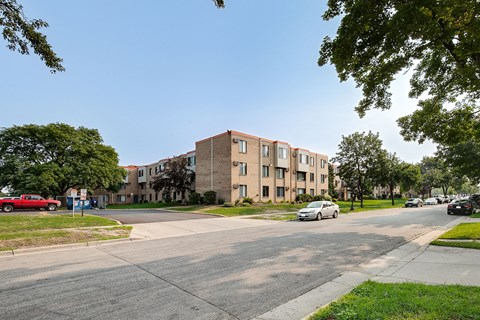 A red car is parked on the side of the road in front of a building.