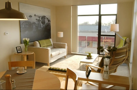 A living room with a couch, chairs, and a table with a vase of flowers on it.