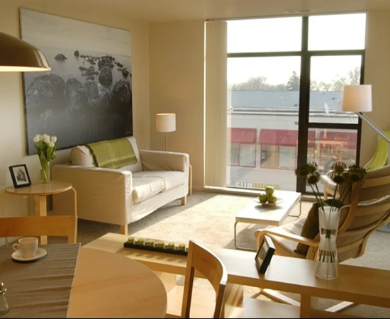 A living room with a couch, chairs, and a table with a vase of flowers on it.