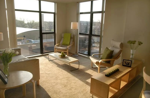 A sunny room with a piano, chairs, and a table.