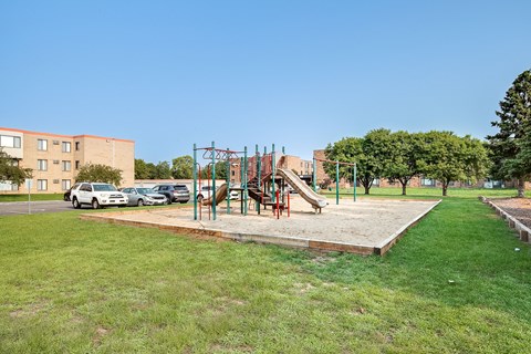A playground with a slide and swings in a grassy area.