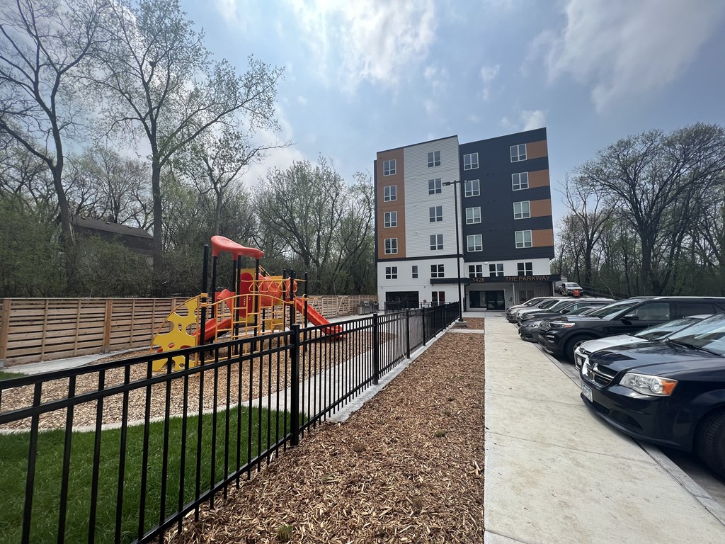 a playground in front of a building with cars parked in a parking lot