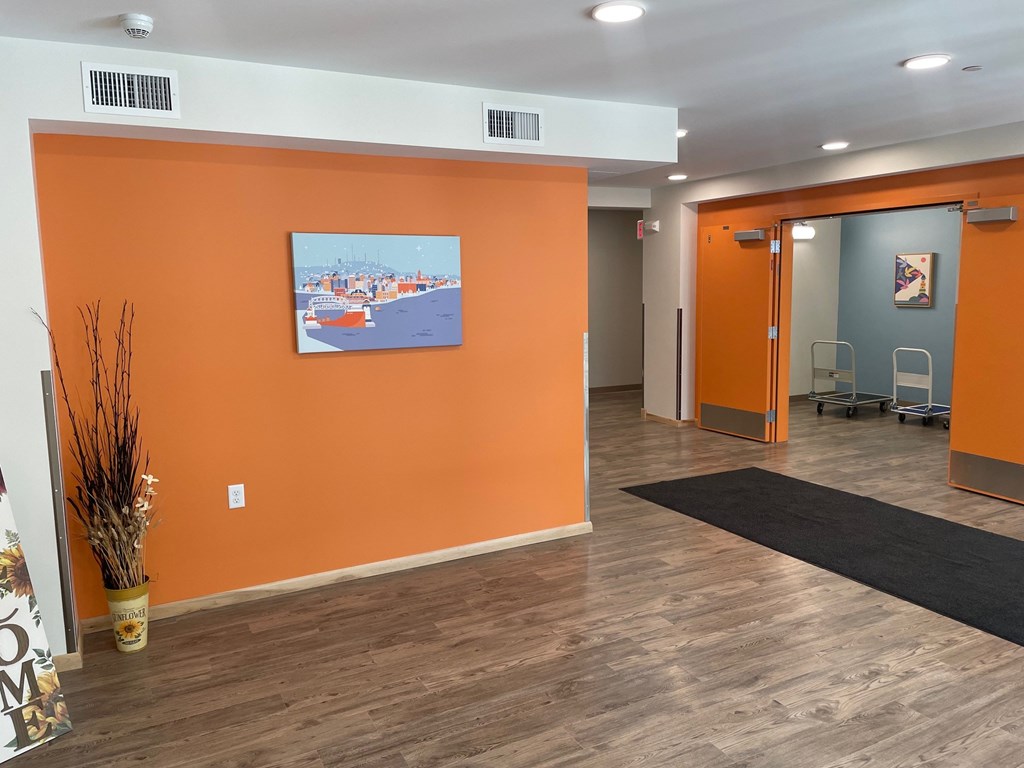 A room with orange walls and a painting of a cityscape.