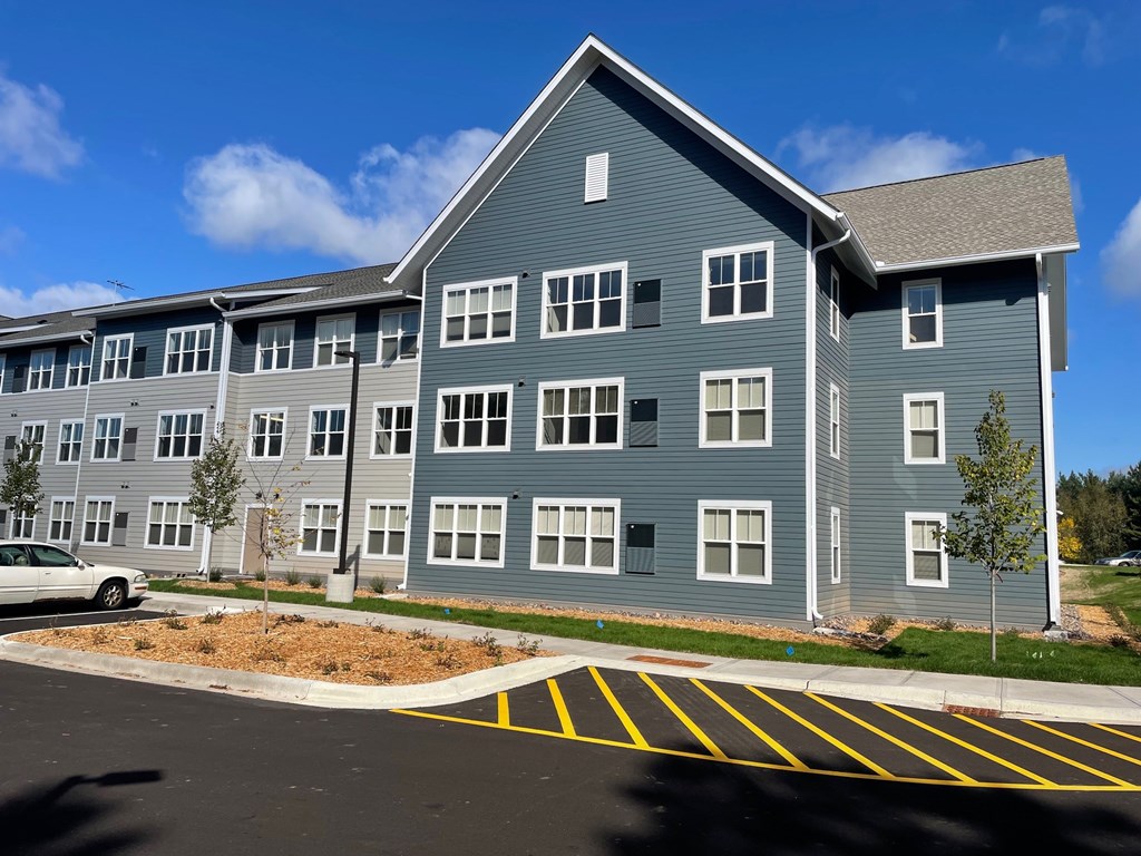 A large grey building with a parking lot in front.