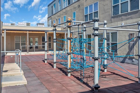 A playground with a blue climbing structure on a brick patio.
