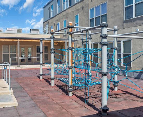 A playground with a blue climbing structure on a brick patio.