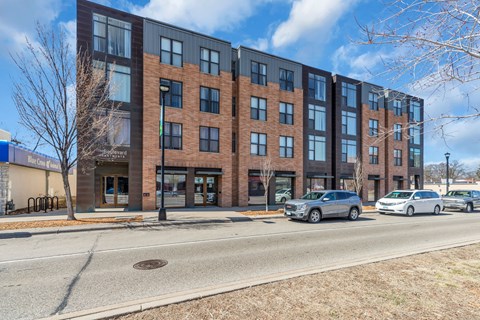 A modern brick building with a parking lot in front.