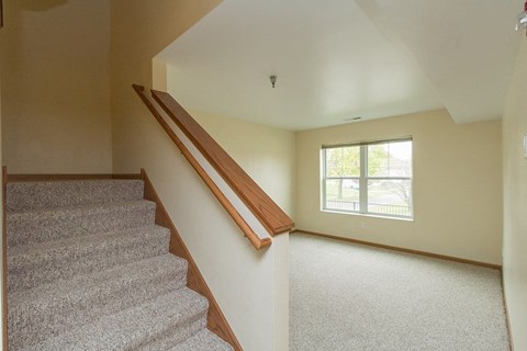 A staircase with a wooden handrail leads up to a window.