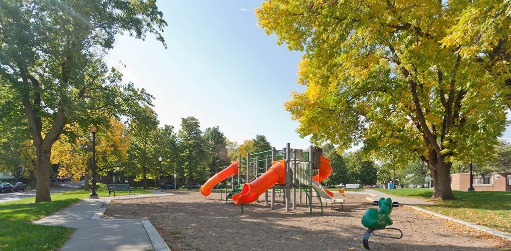 A playground with a red slide and a green bicycle.