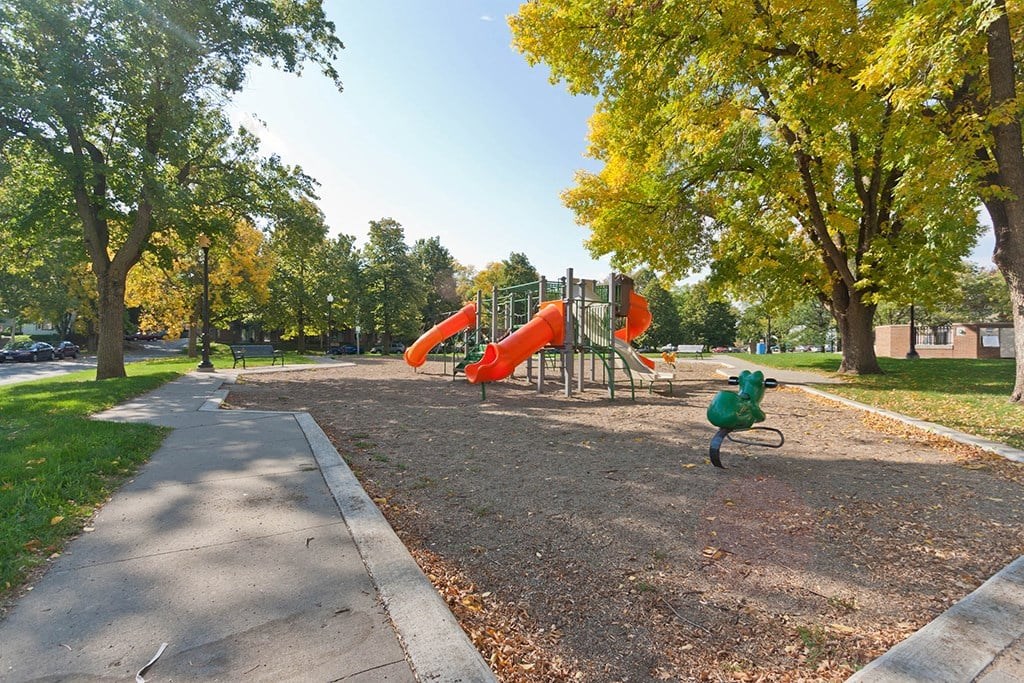 A playground with a red slide and a green ball.