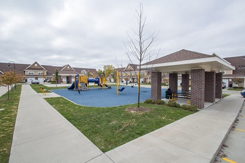A playground with a blue slide and a brown pavement.