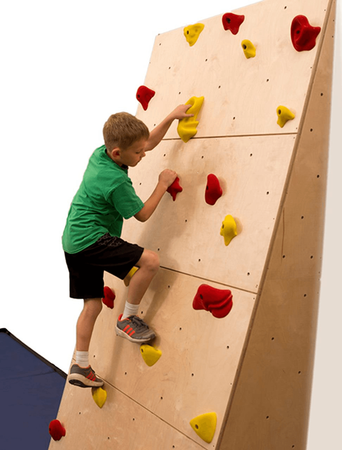A boy climbing a wall with red and yellow holds.
