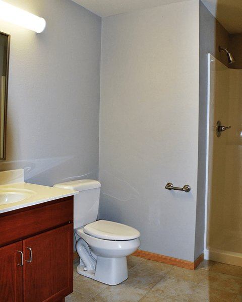 A white toilet sits in a bathroom next to a sink and a shower.
