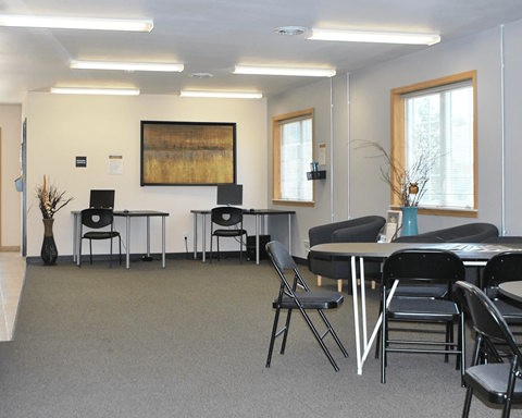 A conference room with a grey carpet and black chairs.