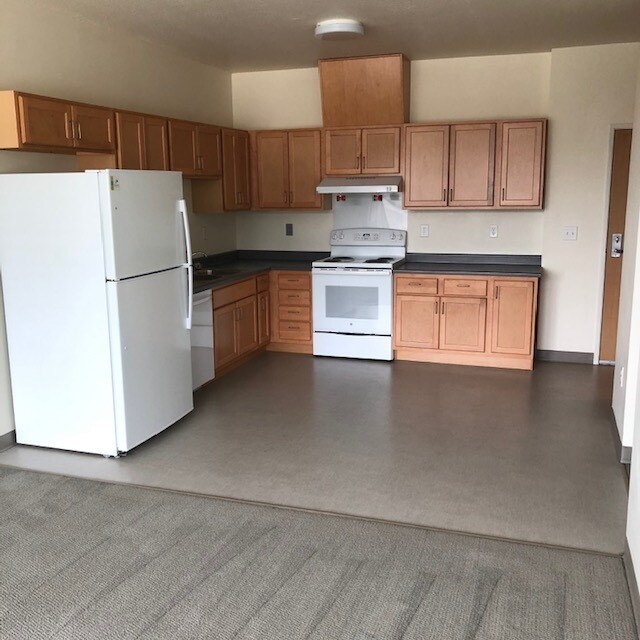 A white refrigerator is in a kitchen with wooden cabinets.