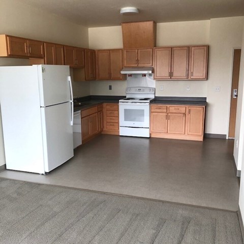 A white refrigerator is in a kitchen with wooden cabinets.