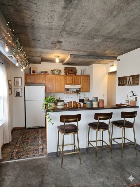A kitchen with a white refrigerator and wooden cabinets.