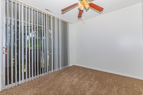 A room with a carpeted floor and a ceiling fan.
