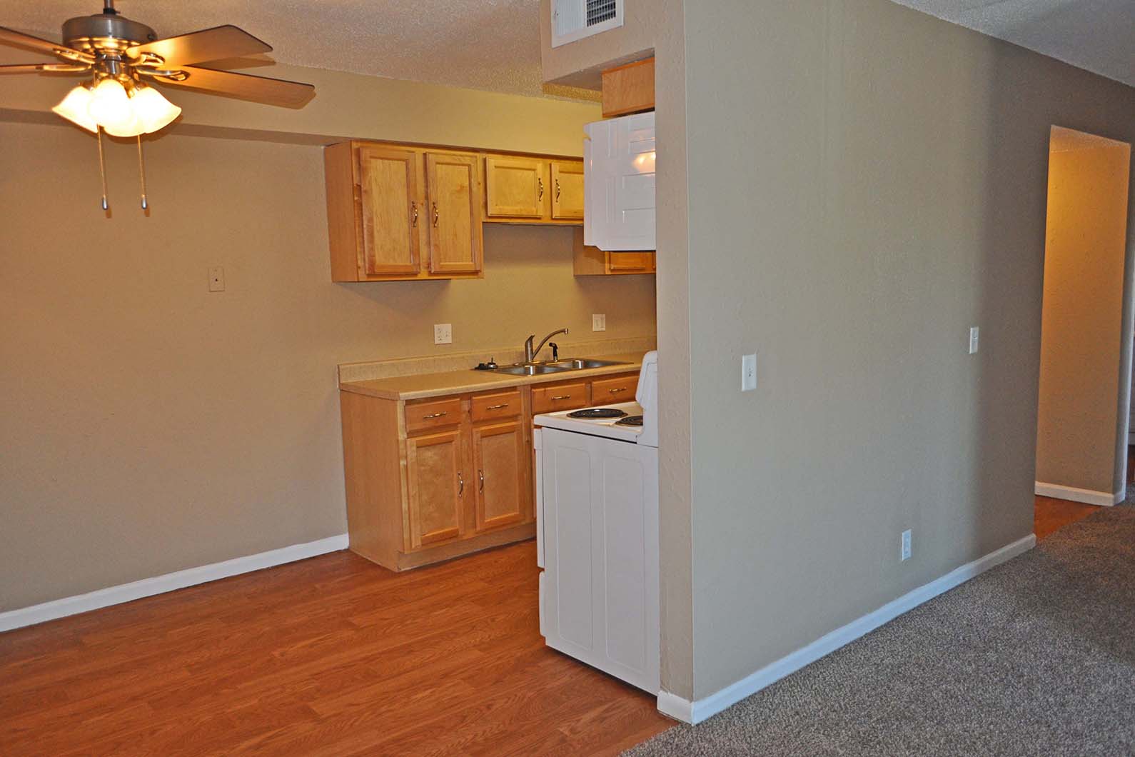 an empty kitchen with a ceiling fan and wooden floors