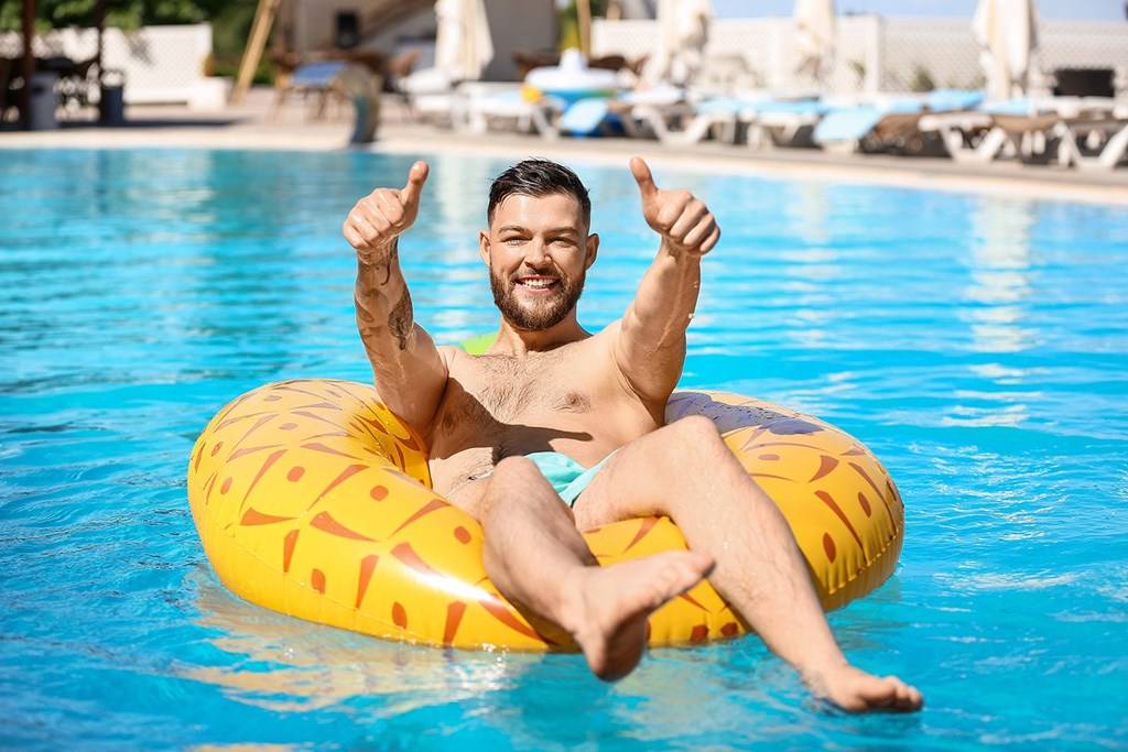 A man is sitting on a yellow inflatable ring in a pool.