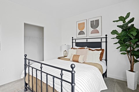 A bedroom with a black metal bed frame and a potted plant on the side table.