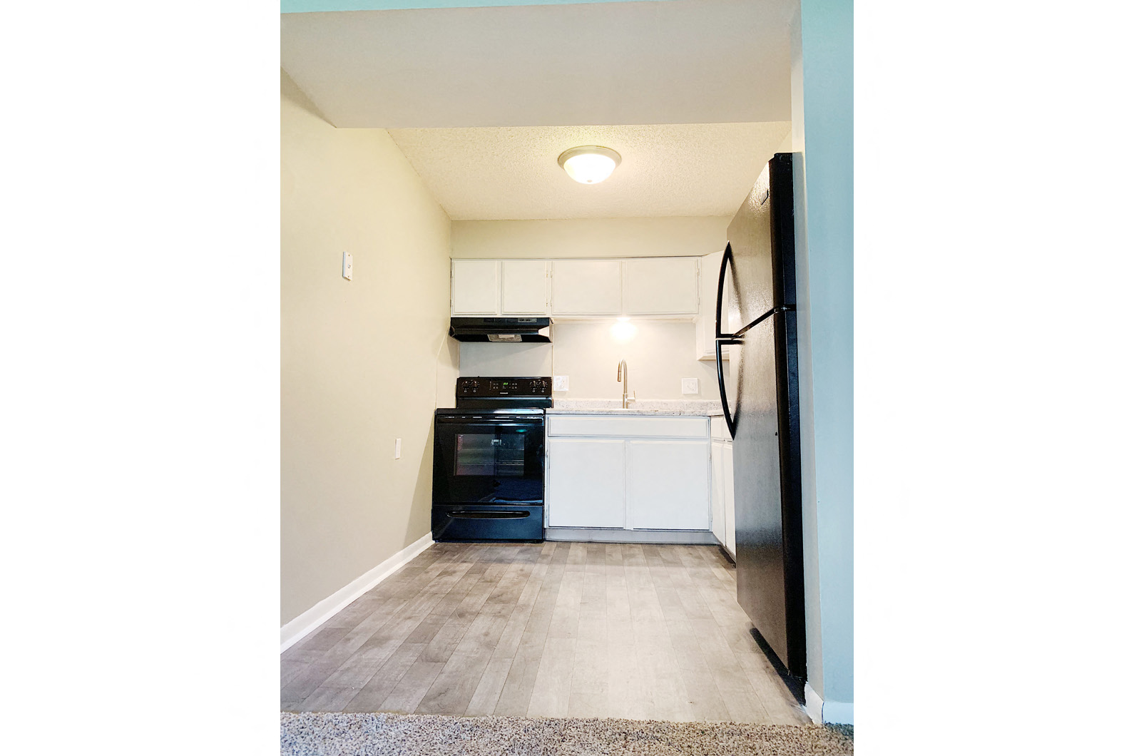 a kitchen with white cabinets and a black stove and refrigerator