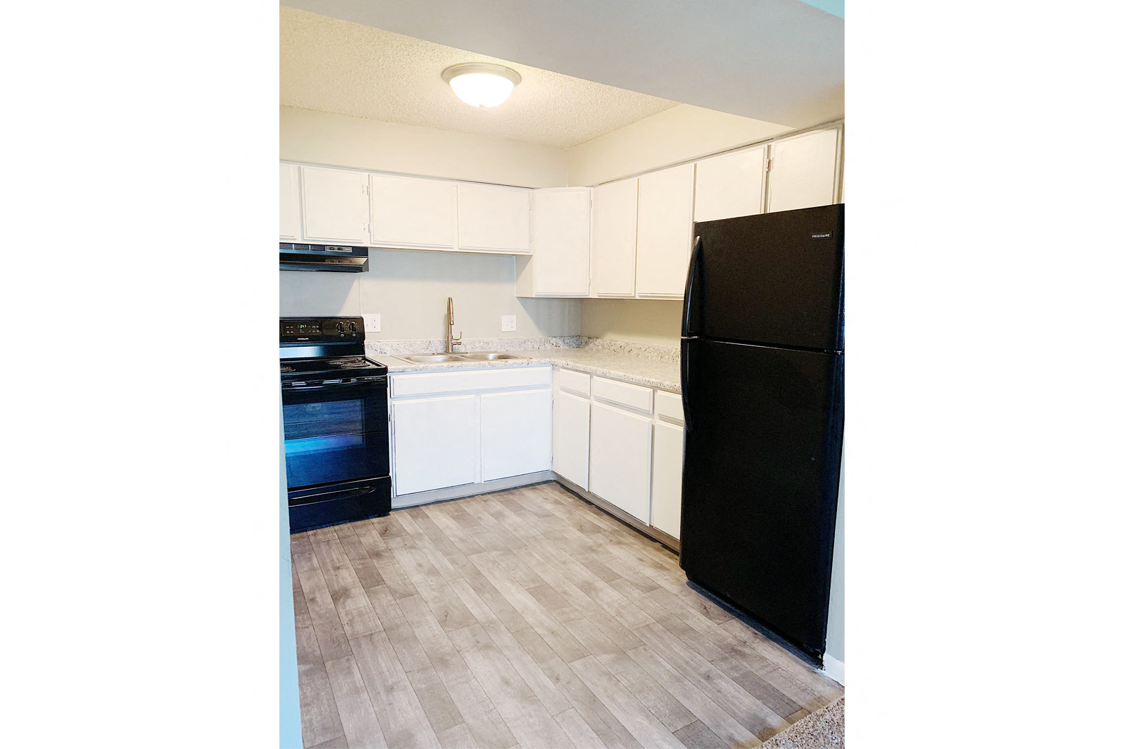 a kitchen with white cabinets and a black refrigerator