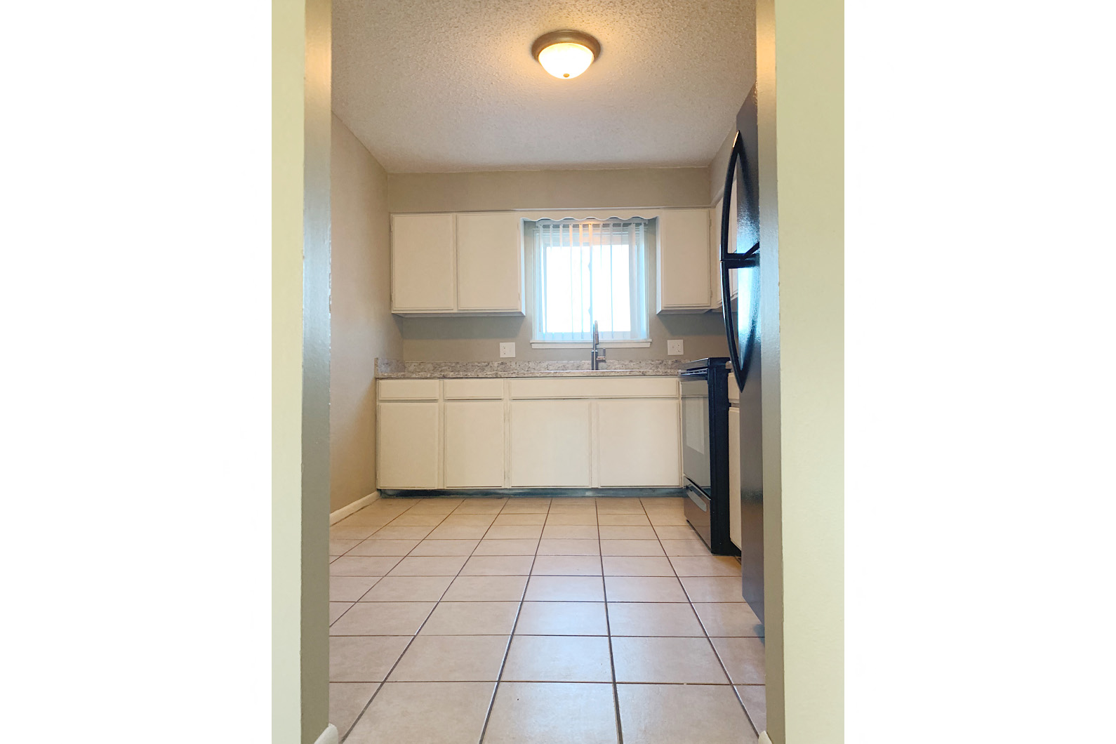 a view of a kitchen with white cabinets and a window