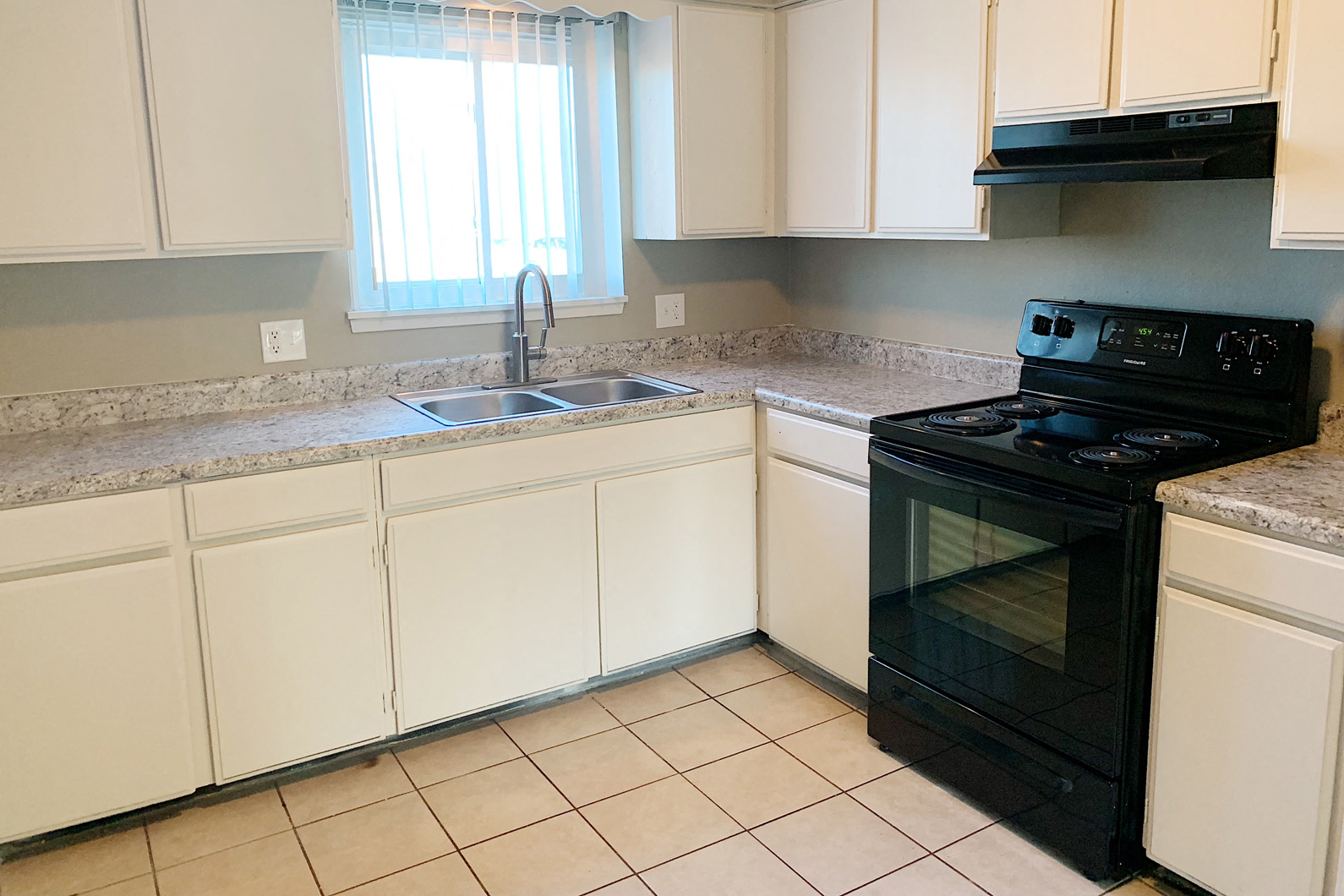 a kitchen with white cabinets and a black stove and a sink