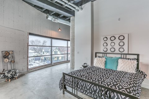 A bedroom with a large bed and a large window.