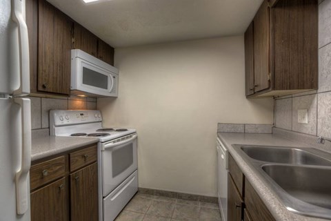 A kitchen with a white refrigerator, white stove, and a white microwave.