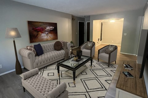 A living room with a white couch, a coffee table, and a painting on the wall.