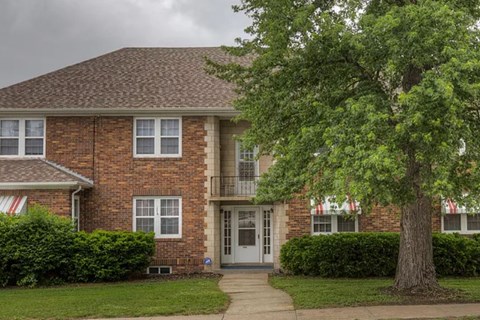 A brick house with a tree in front.