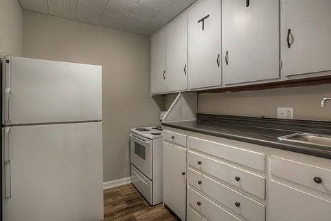 A white refrigerator stands next to a white oven in a kitchen.
