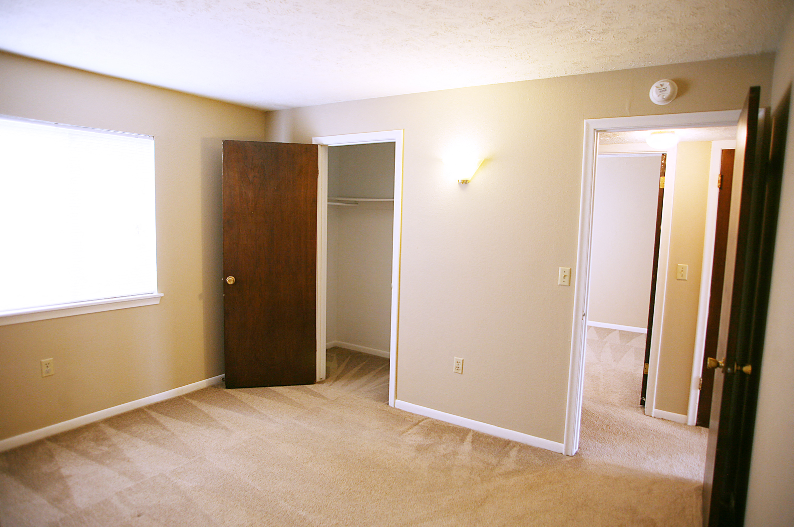 an empty room with a door to a closet and a window