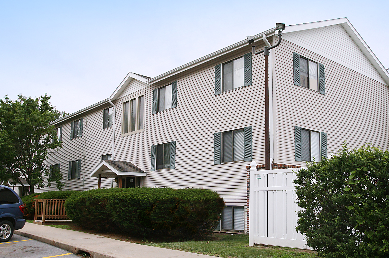 an apartment building with a white facade and a white fence