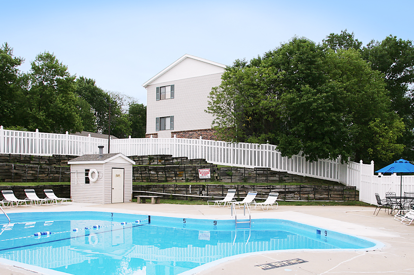 a swimming pool with a white fence and a house in the background