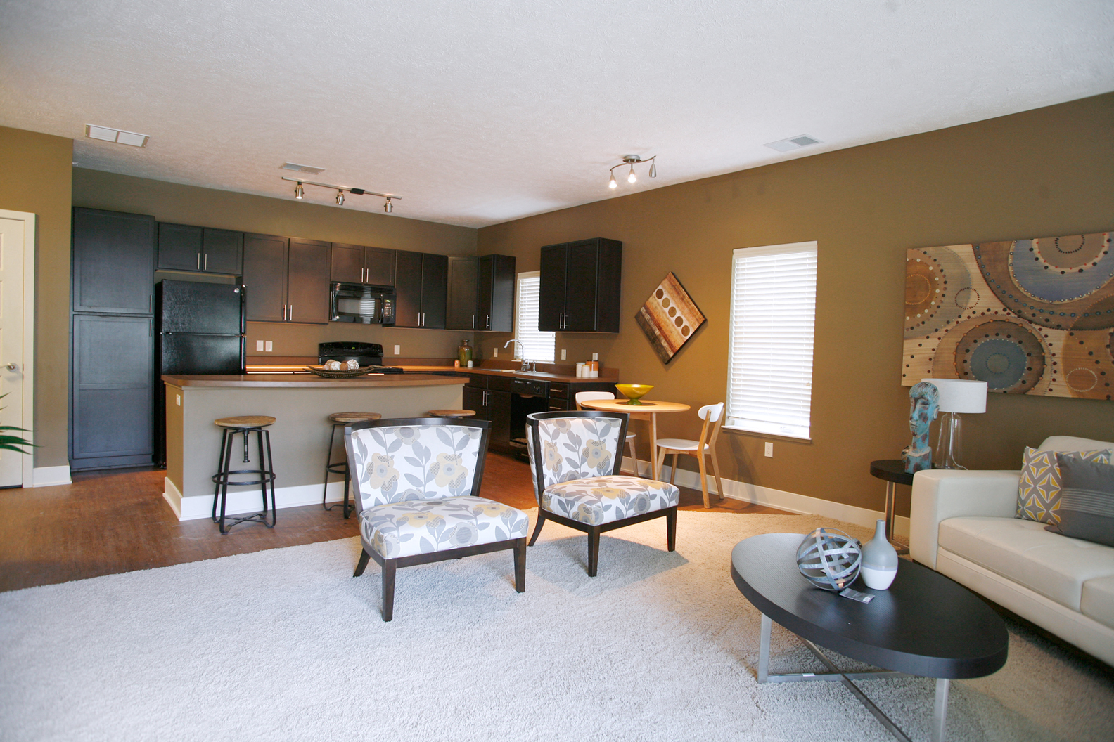 a living room with a kitchen and a couch and chairs