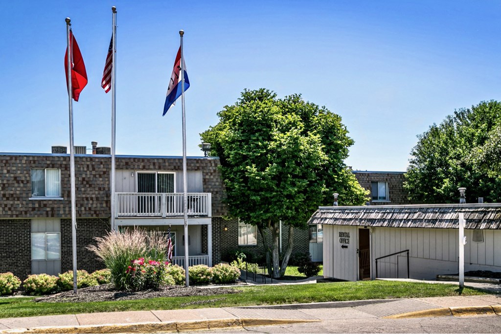 three flags flying in front of an apartment building