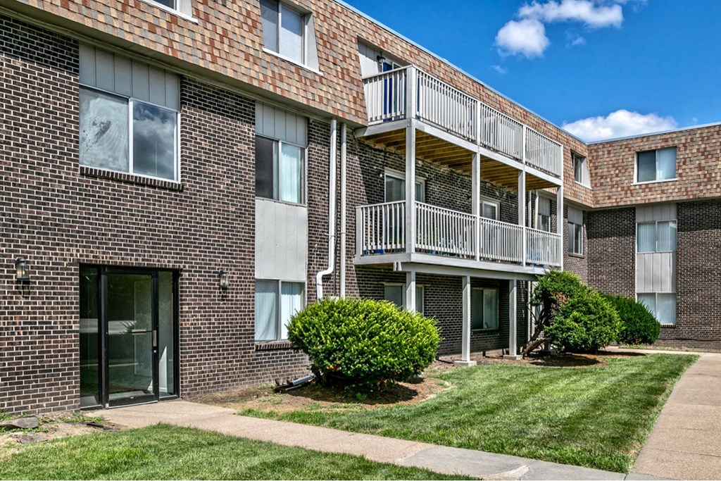 a brick apartment building with a balcony and a lawn
