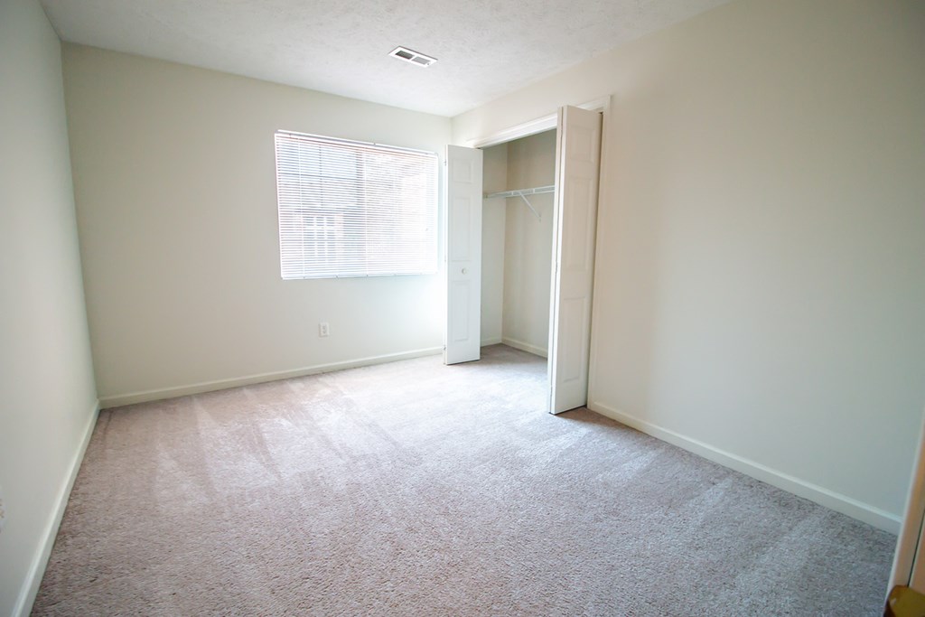 an empty room with a closet and a window