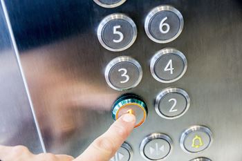 a hand pressing a button in an elevator