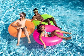 three people sitting on inner tubes in a pool